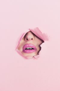 Model with lip filler in Glasgow bursting through pink paper
