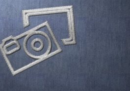 Silver Stitched Camera Logo on Blue Material