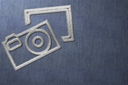 Silver Stitched Camera Logo on Blue Material