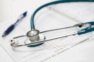 Notebook, stethoscope and safety pin lying on desk of lip fillers in Glasgow clinic 